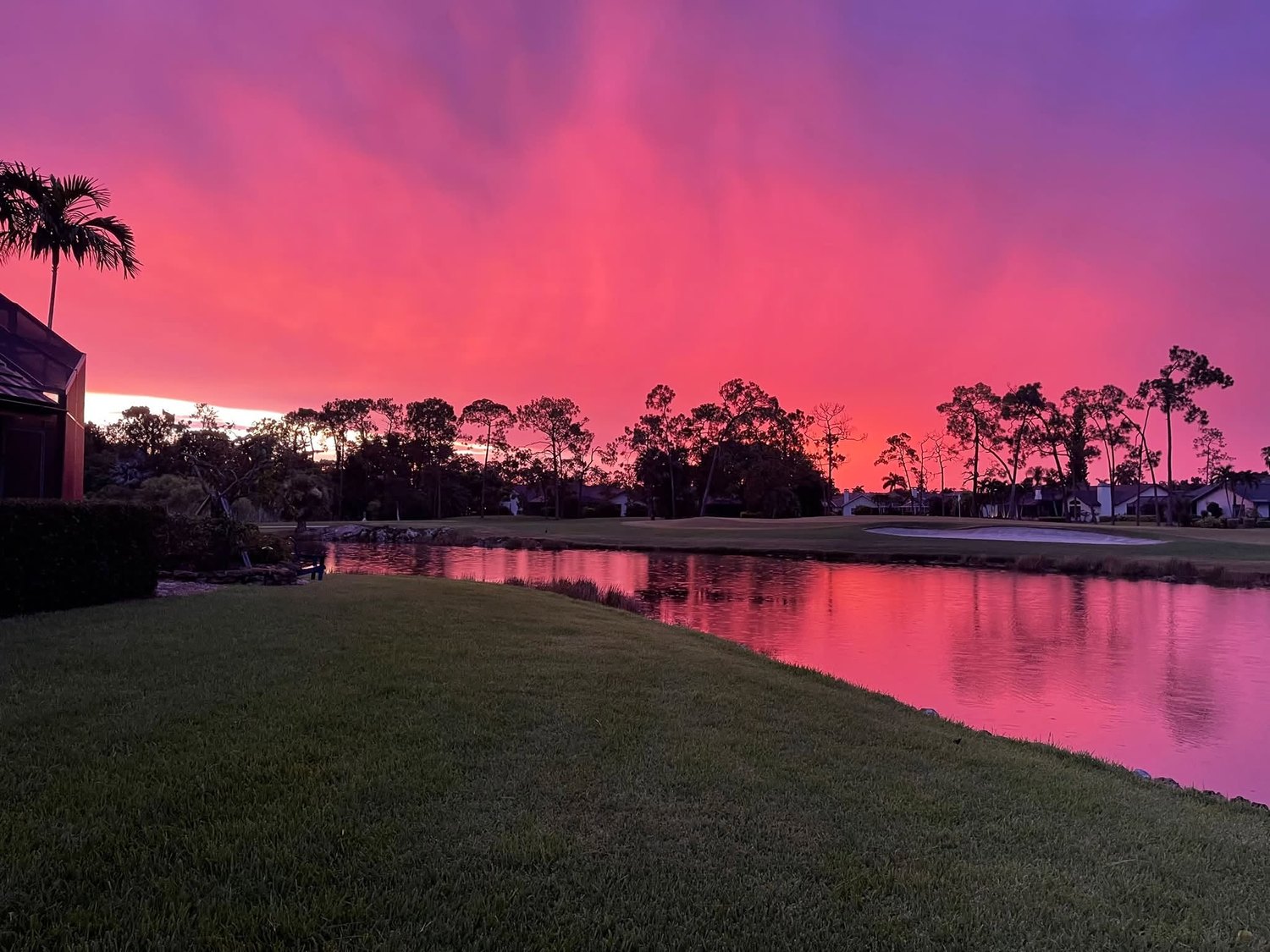 Vivid pink sunset reflected in a lake along the golf course